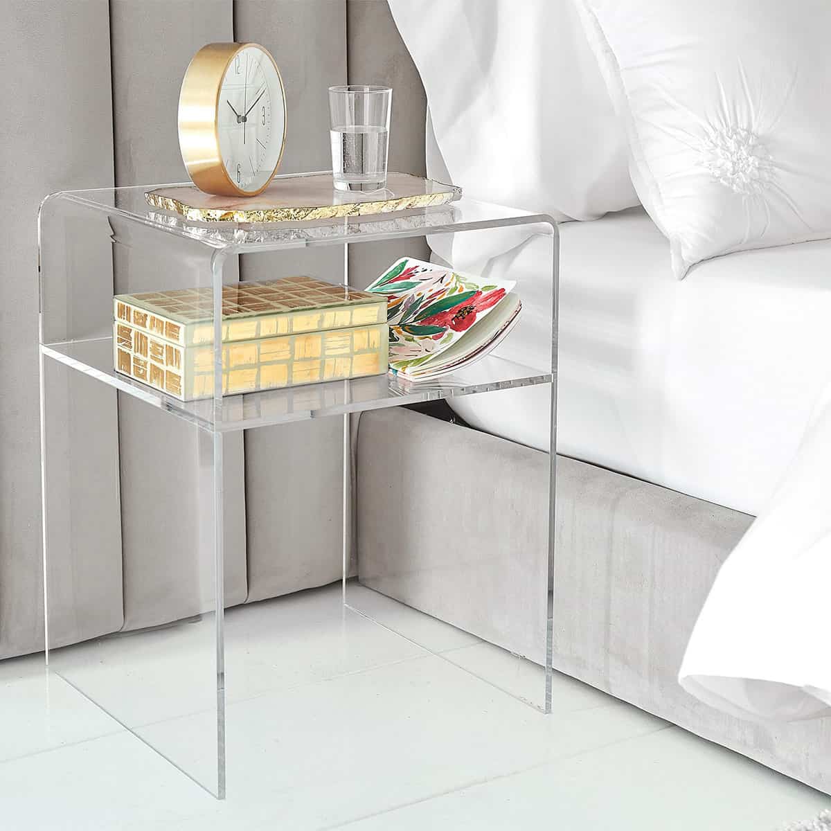Clear acrylic nightstand with large gold clock atop gold tray, gold & white trinket box.