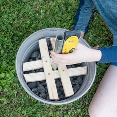 Boy holding level to the smaller pole to make sure it is level.