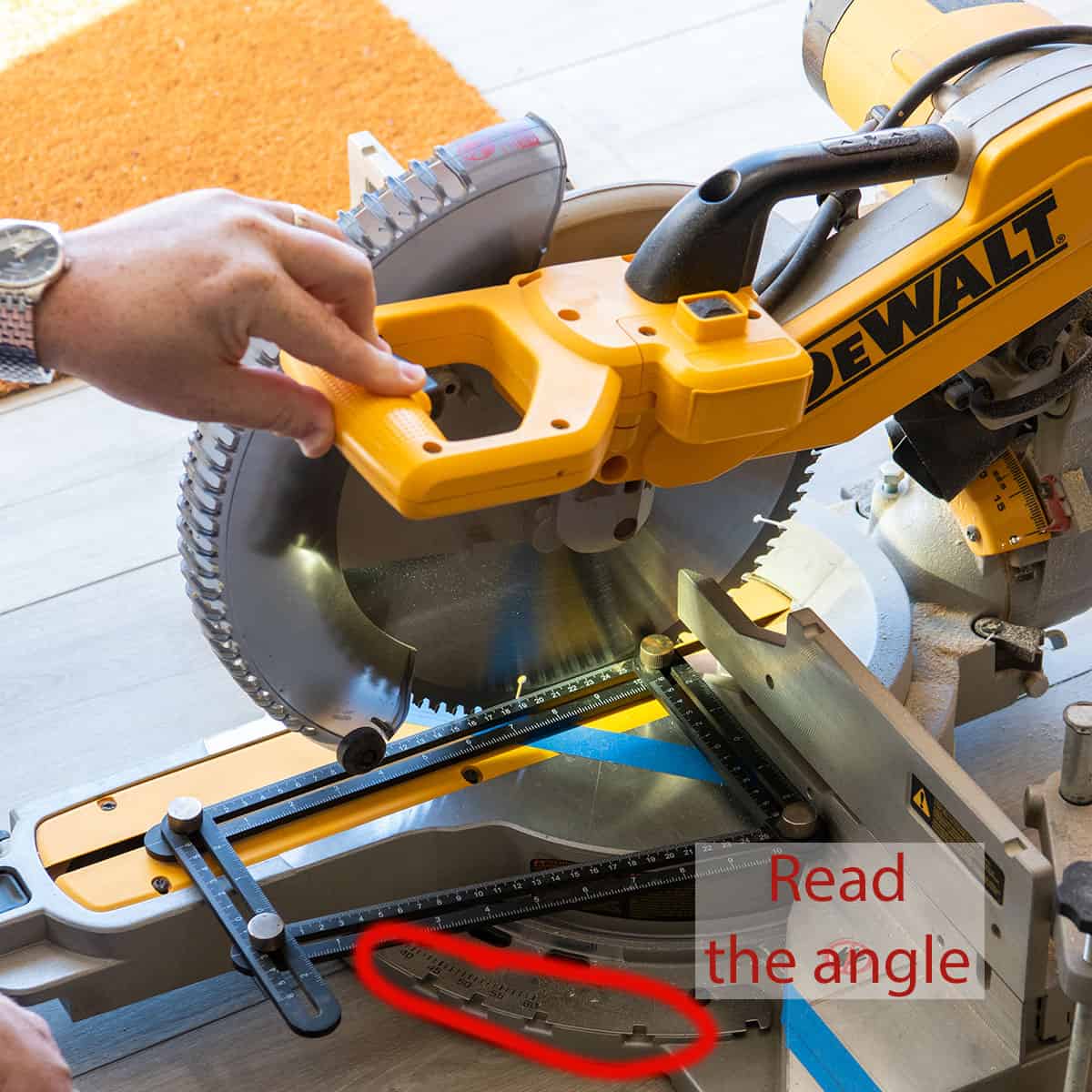 Man using a miter saw to read the angle from a wood protractor.