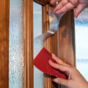 Hands applying window film and getting rid of bubbles.