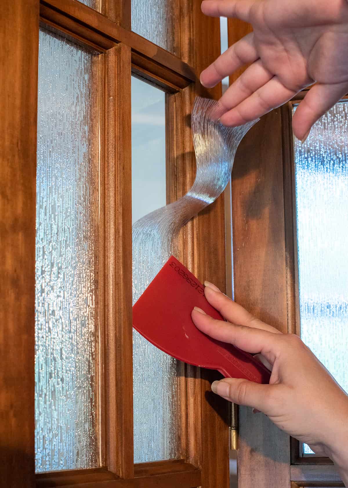 Hands applying window film and getting rid of bubbles.