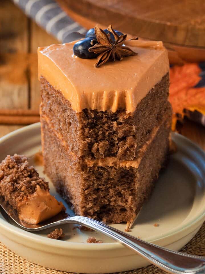 Closeup of a fall layer cake with orange frosting and a fork in front of the cake.