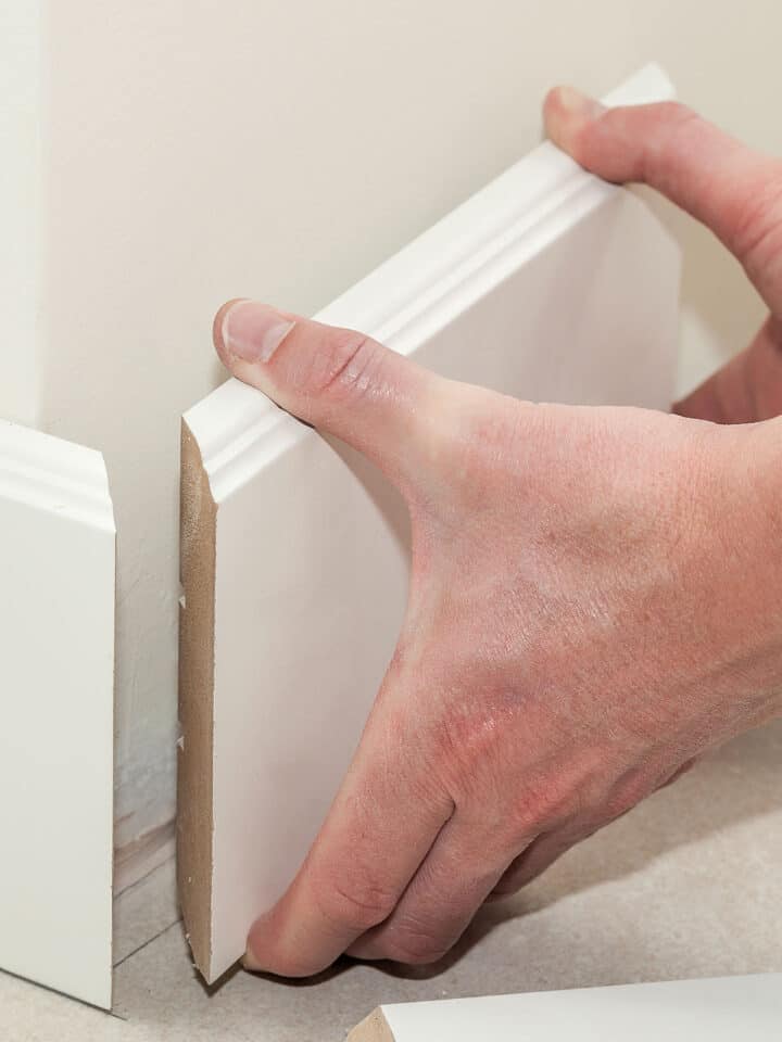 Man holding up baseboards for a corner.