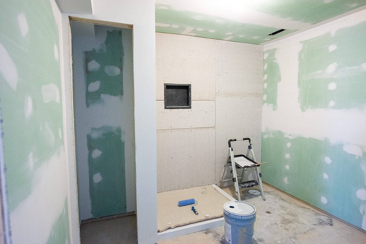 A basement bathroom with green board drywall and concrete board for a shower being installed.