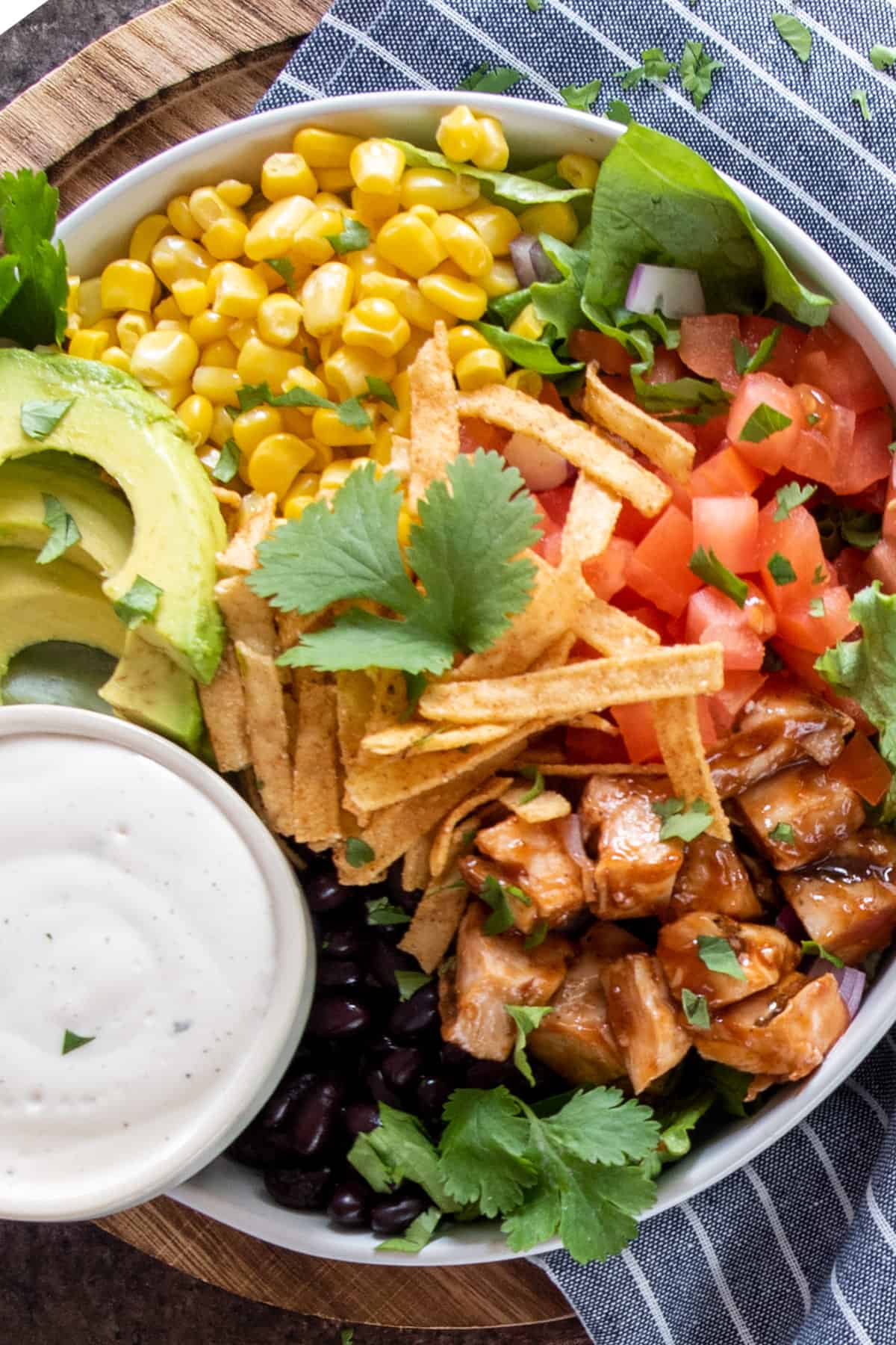 Closeup of BBQ chicken salad toppings including black beans, corn, tomatoes, avocado, and
