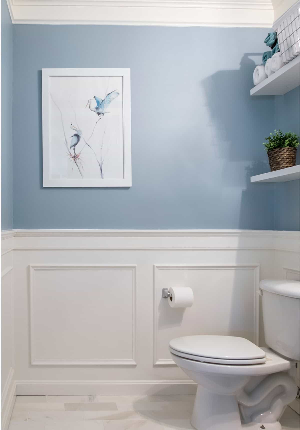 Blue powder room with wainscotting wall and marble floor.