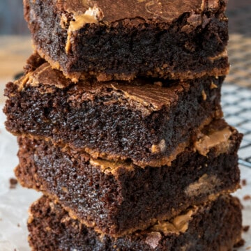 Four Biscoff Brownies stacked high on a wood board.