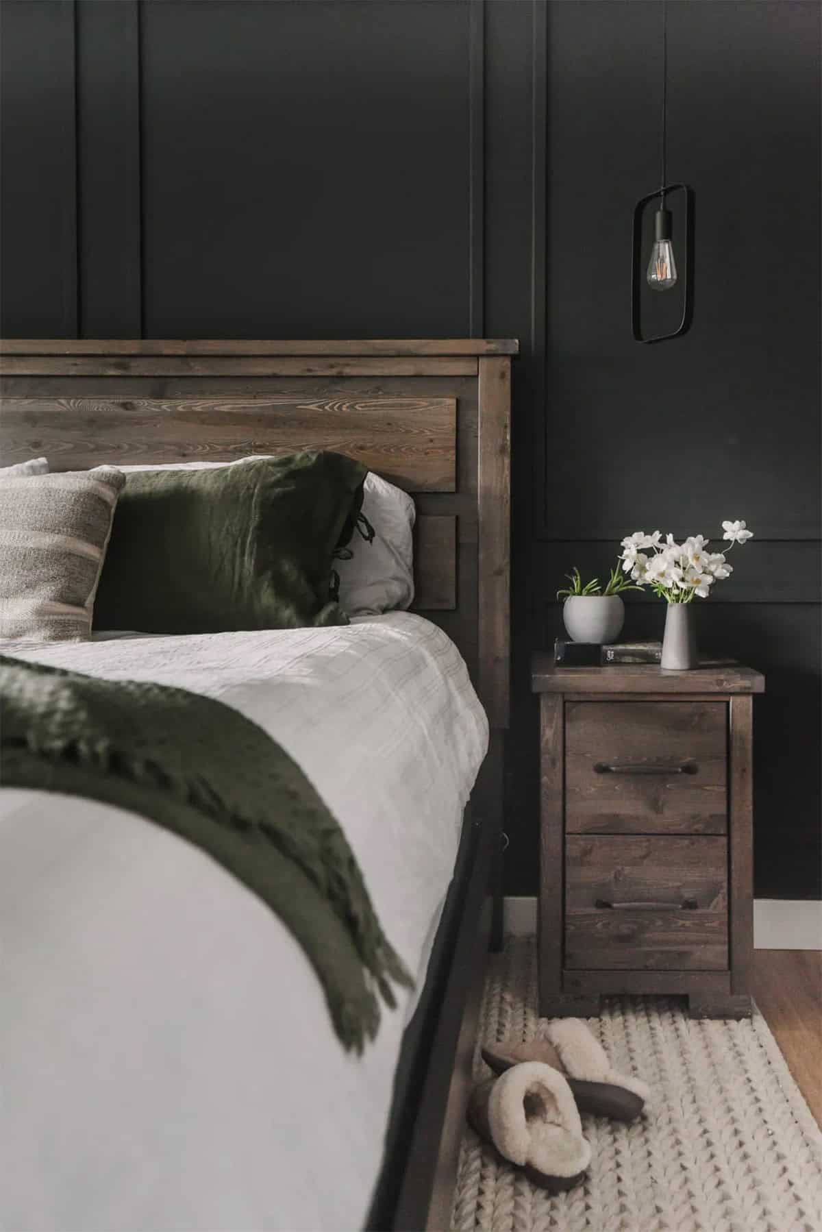 Bedroom with black wall with molding on it and dark wood furniture.