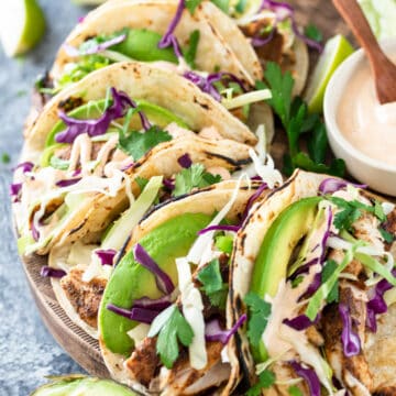 Blackened mahi mahi fish tacos on a platter with mango and sauce.