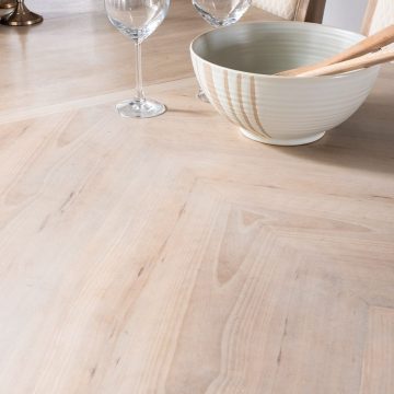Stripped dining room table after. Wood grain pattern revealed. Wine glasses and white salad bowl with natural accents and wooden utensils for ambiance.