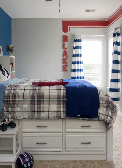 Boys bedroom in grey and navy with red accents and a red racing stripe painted on the wall.