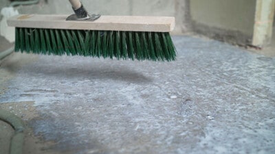 Push broom scrubbing garage floor.