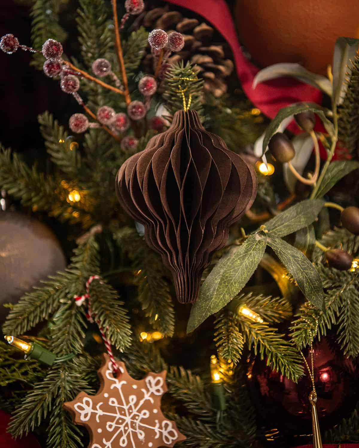 A folded paper accordion ornament in chocolate brown on a Christmas tree.