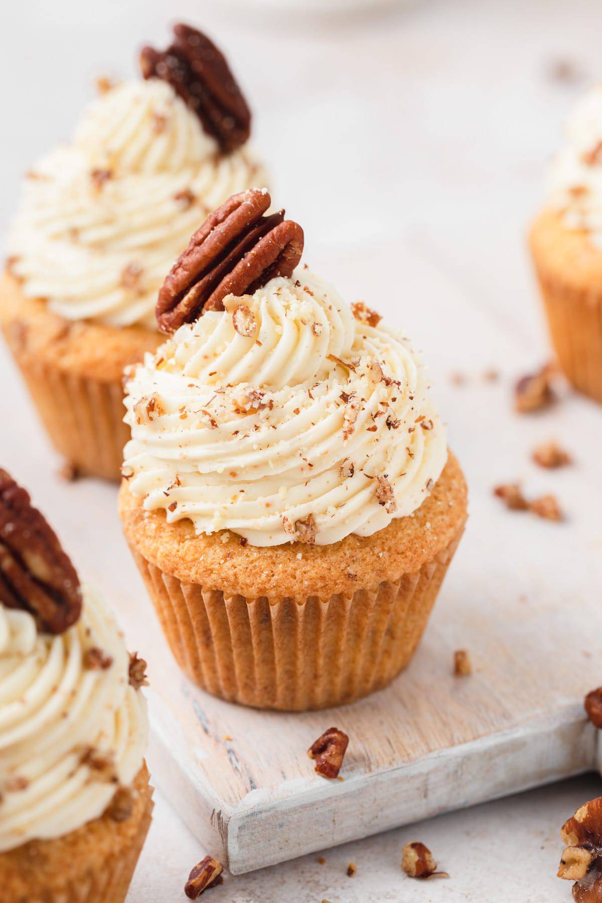 Brown butter pecan cupcakes with chopped pecans on brown buttercream frosting.