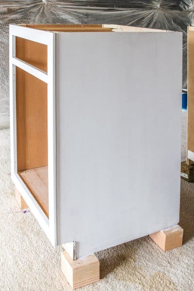 White base cabinet with doors removed on painting blocks.