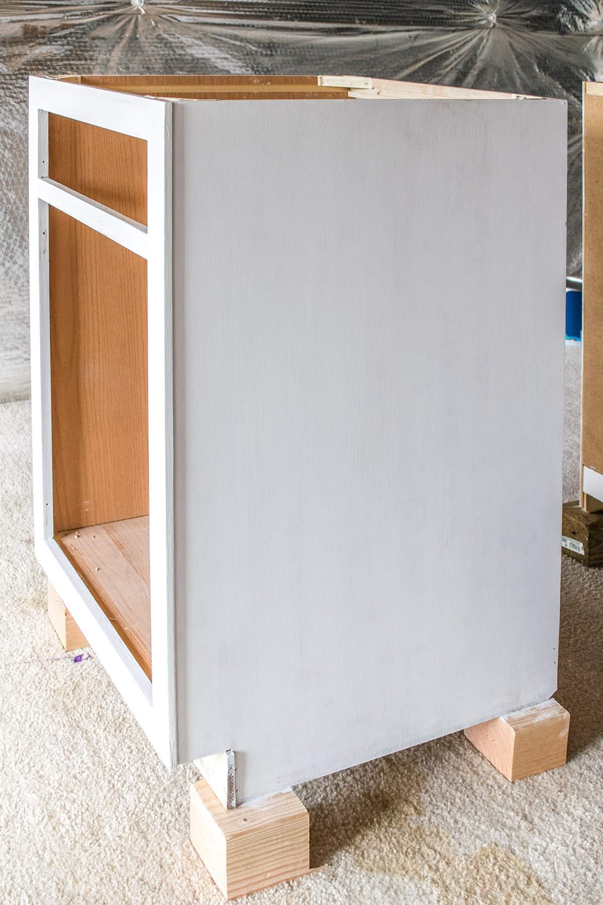 Cabinet section painted white with doors removed, propped up from the floor.