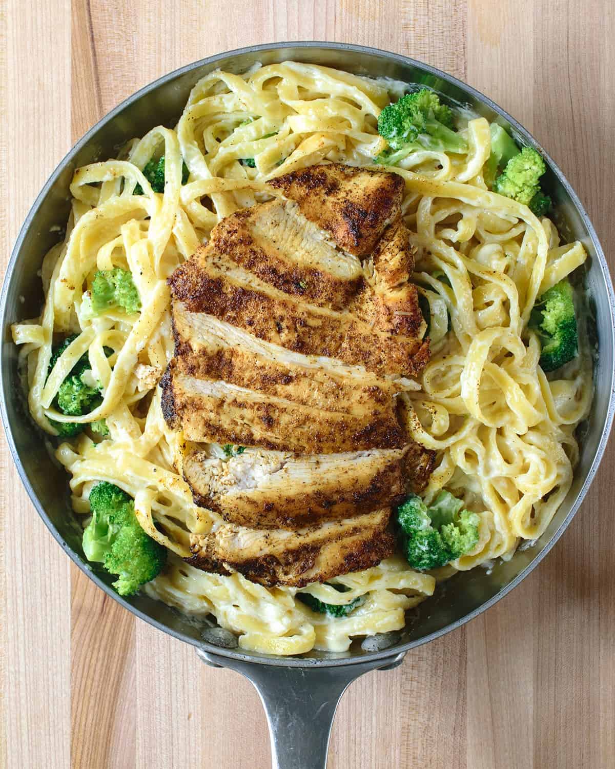 Easy Cajun Chicken Alfredo pasta with homemade Alfredo sauce with broccoli and shredded parmesan in skillet