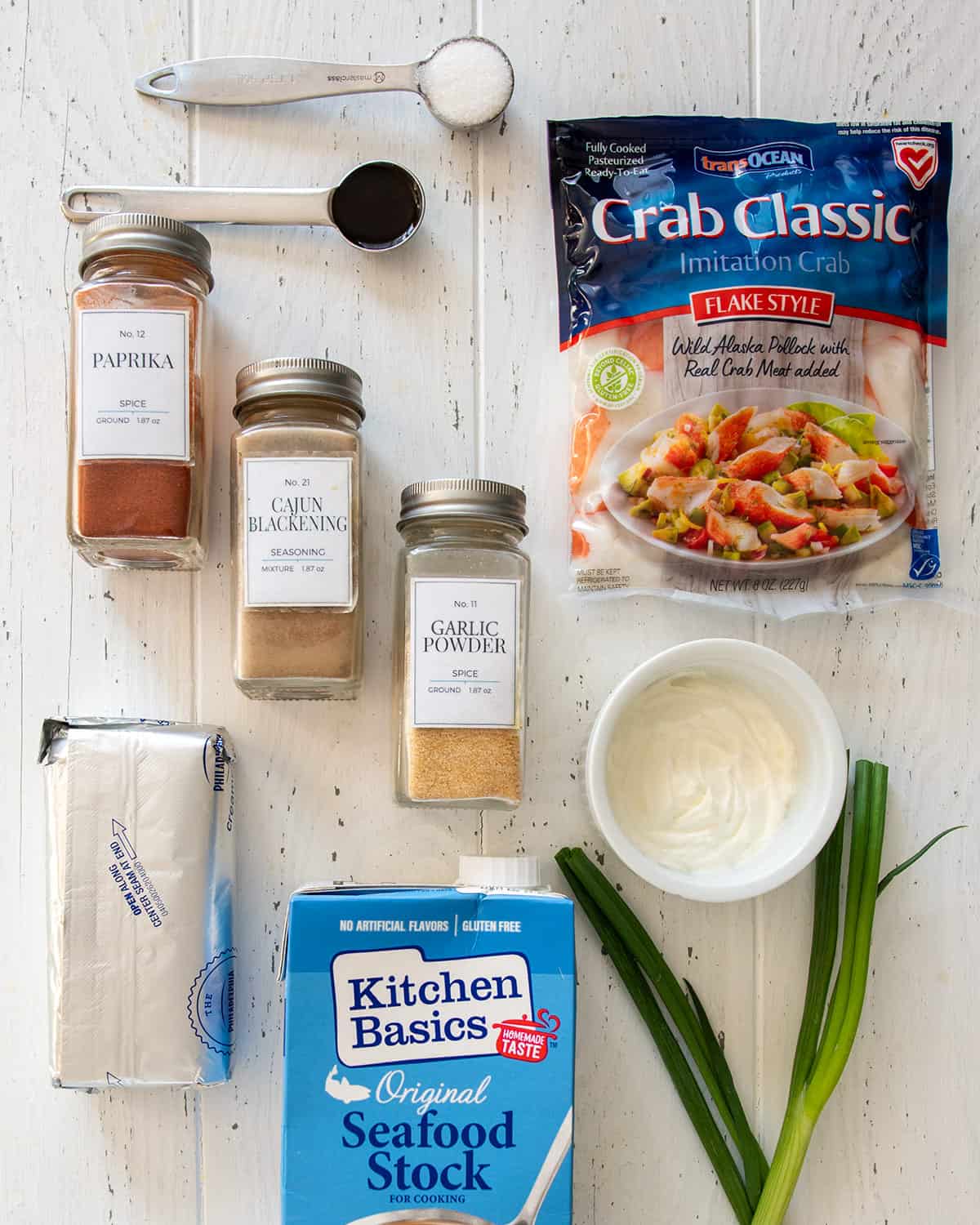 Ingredients for Imitation crab dip on a table including surimi, cream cheese, seafood stock, and spices.