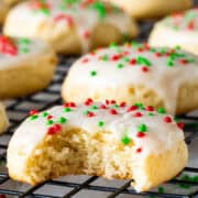 Close up of a sour cream cookie with red and green sprinkles and a bite taken out.