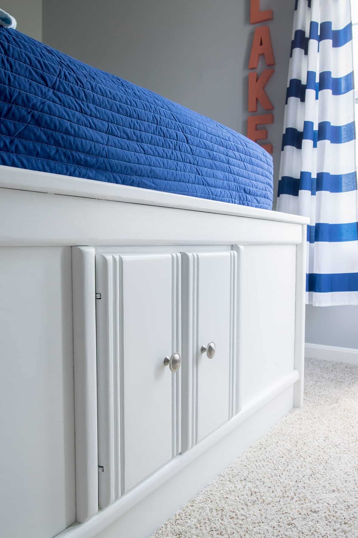 Captain's bed with cabinet storage in white finish with satin nickel hardware.