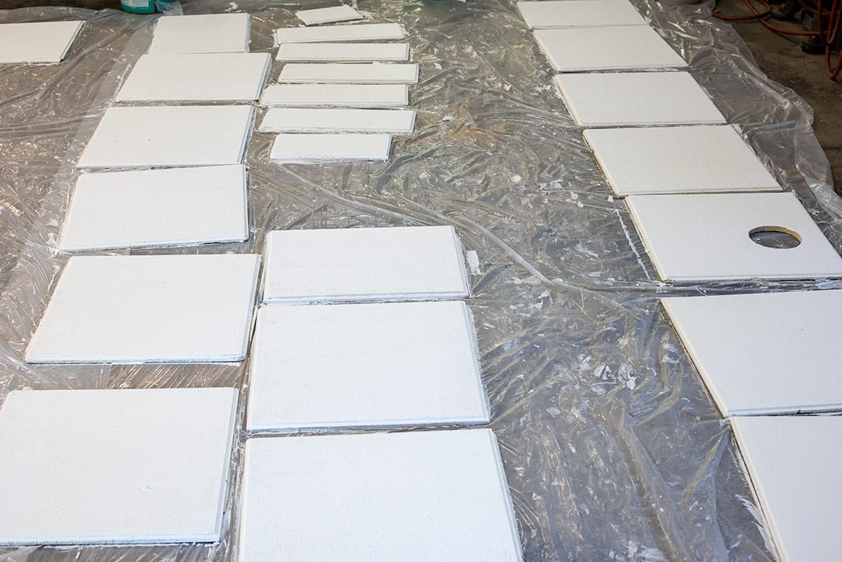 A group of acoustic ceiling tiles laid out on the floor for painting.