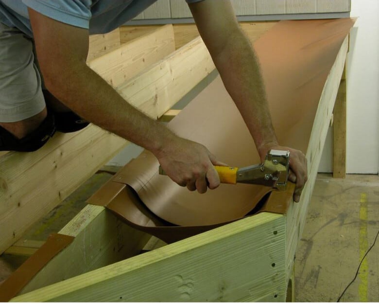 Man hammering in a rubber trough for an under deck ceiling.