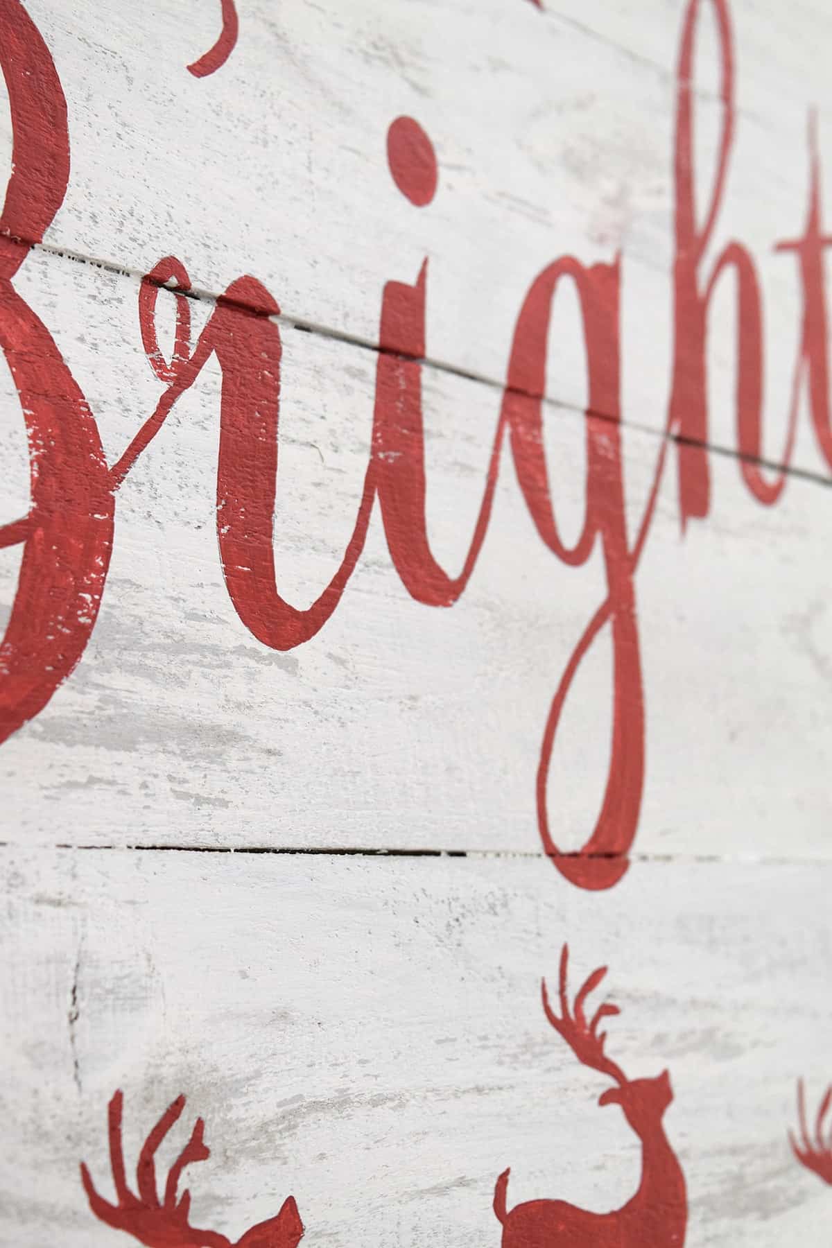 Closeup of Merry and Bright red and white distressed Christmas sign with red lettering.