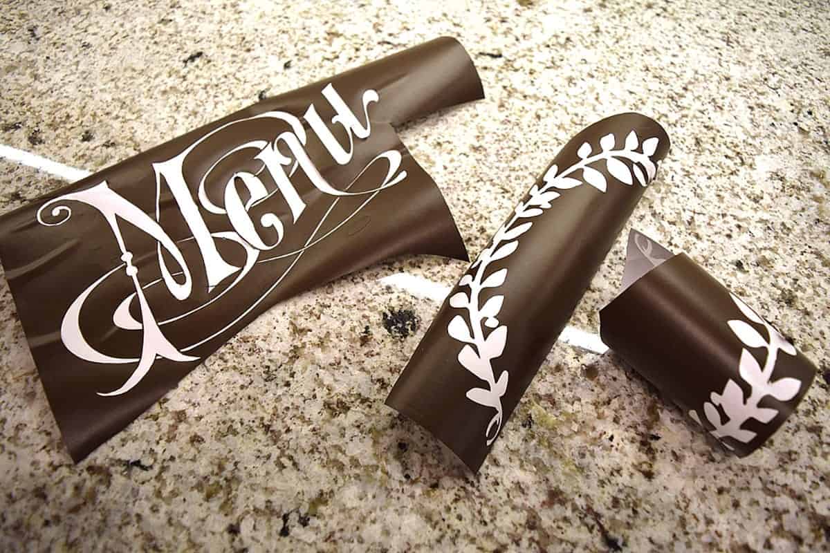 Black vinyl with white menu lettering and decorative detail on marble surface.