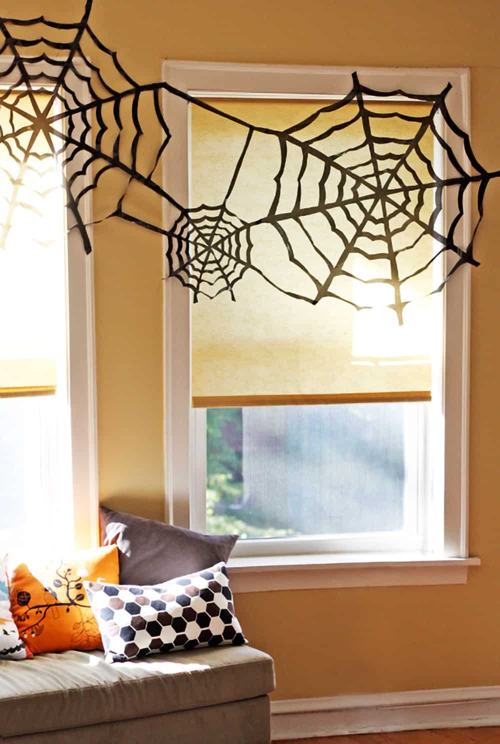 DIY trash bag spider webs as window decorations.