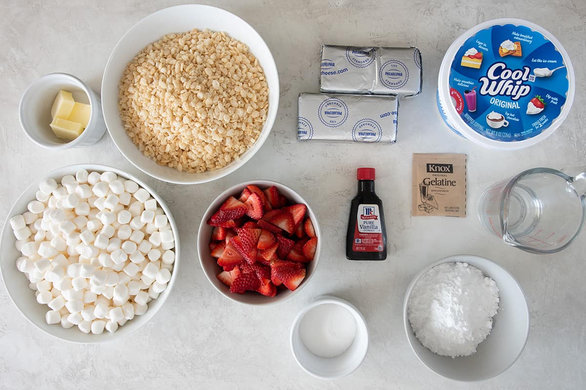 Ingredients for cheesecake rice krispie treat bars laid out on a table with text labels.