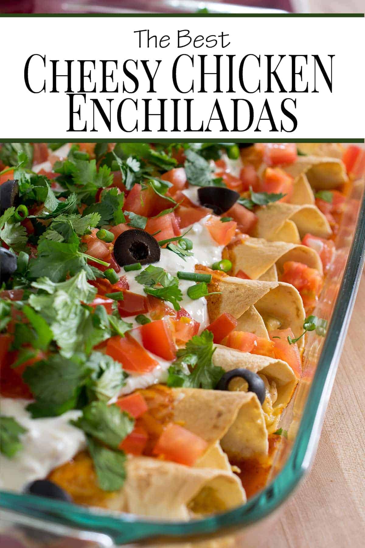 Chicken enchiladas topped with sour cream, pico de gallo, olives and sour cream in baking dish.