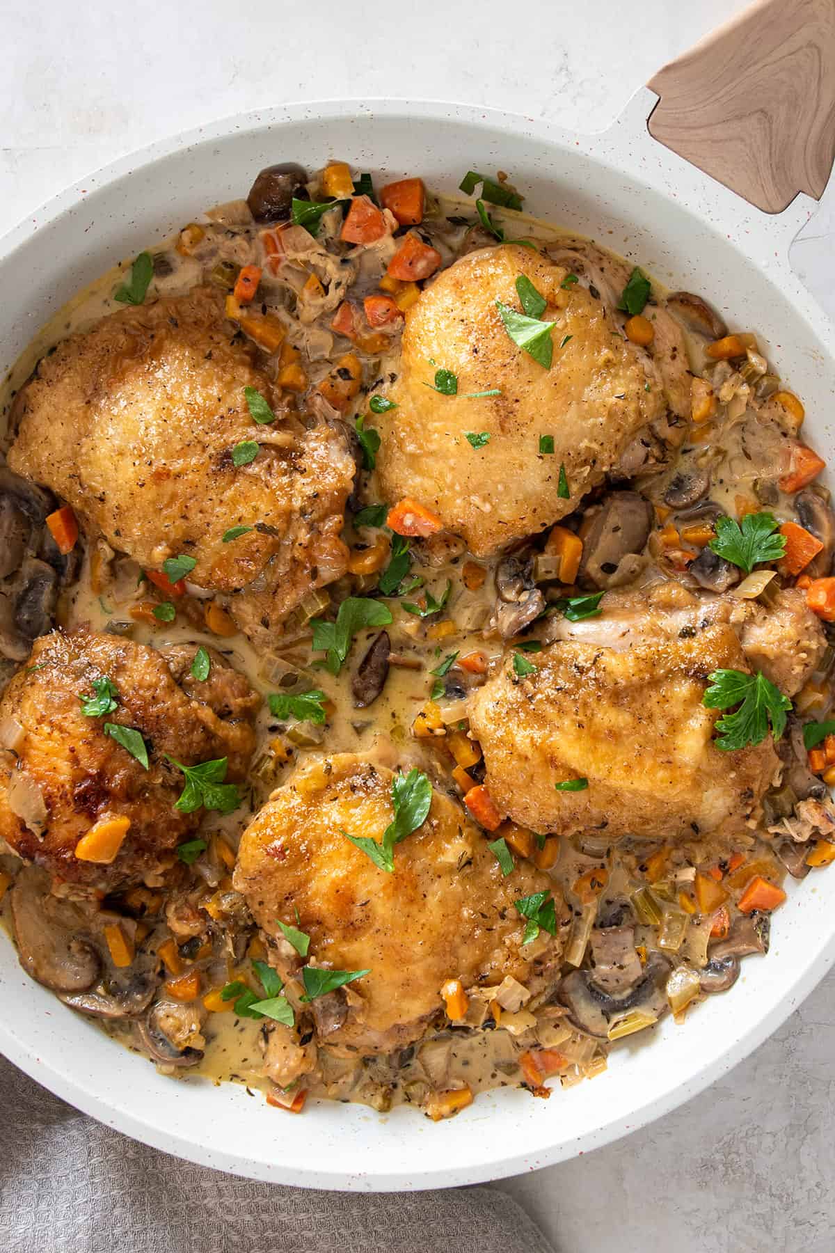Closeup of a skillet of braised Chicken Fricassee with crispy chicken in a white wine sauce.