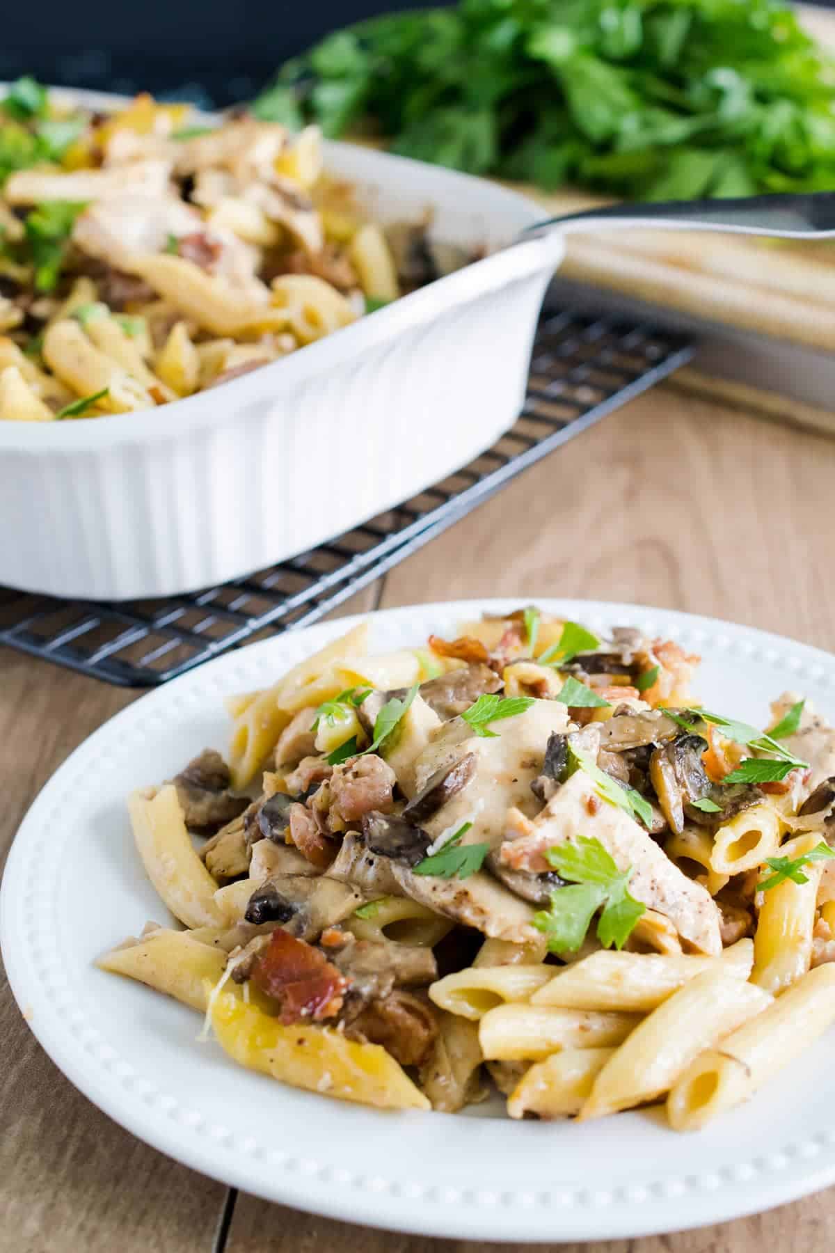 Chicken marsala pasta topped with mushrooms, prosciutto, and creamy Parmesan cheese served on a white plate