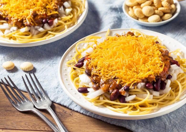 Cincinnati Chili on top of spaghetti noodles on two plates.