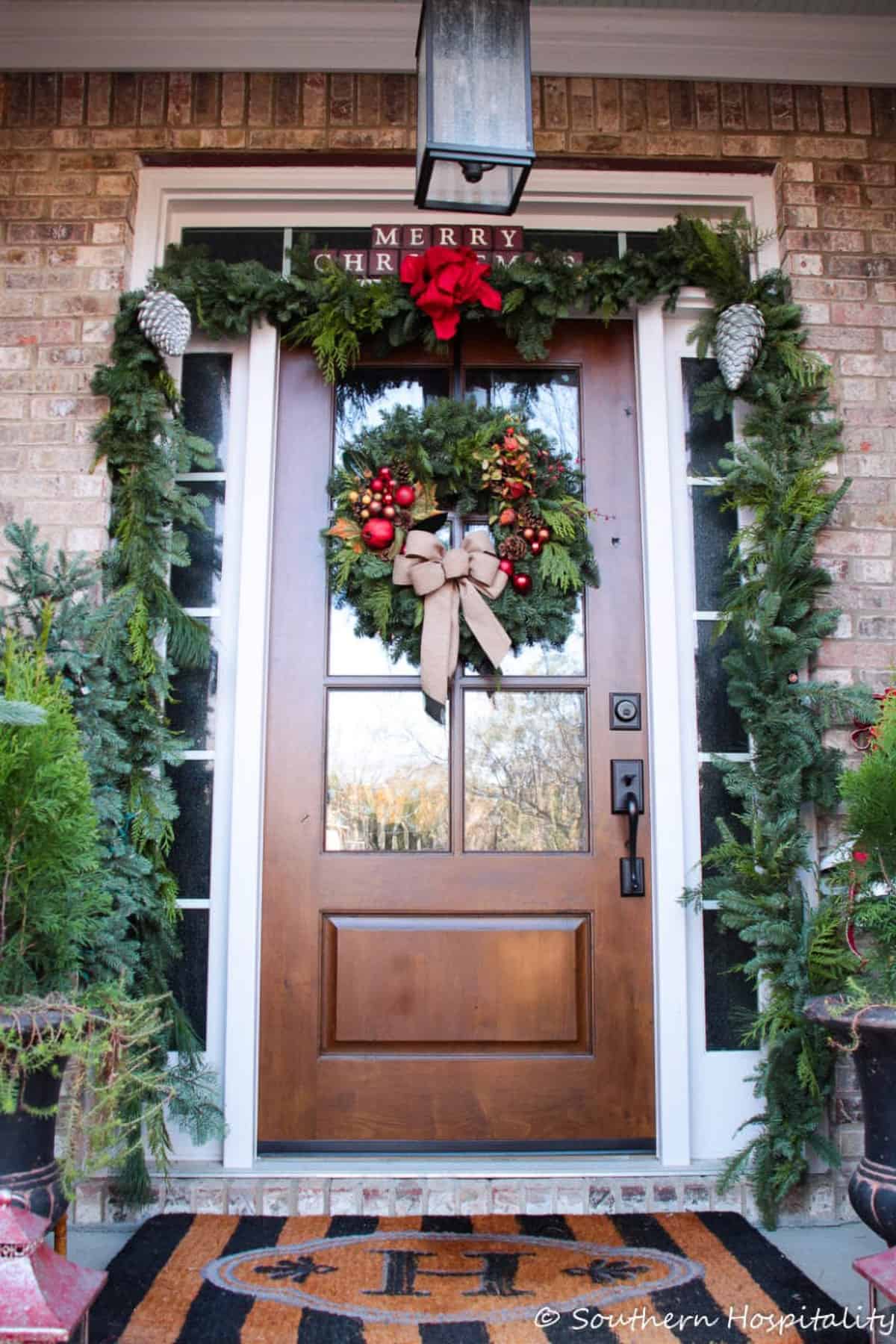 Classic front porch Christmas with fresh wreath and garland around the door.