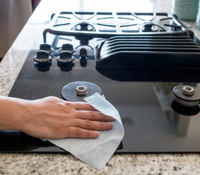 Woman cleaning a glass top stove with a soft wiping cloth.