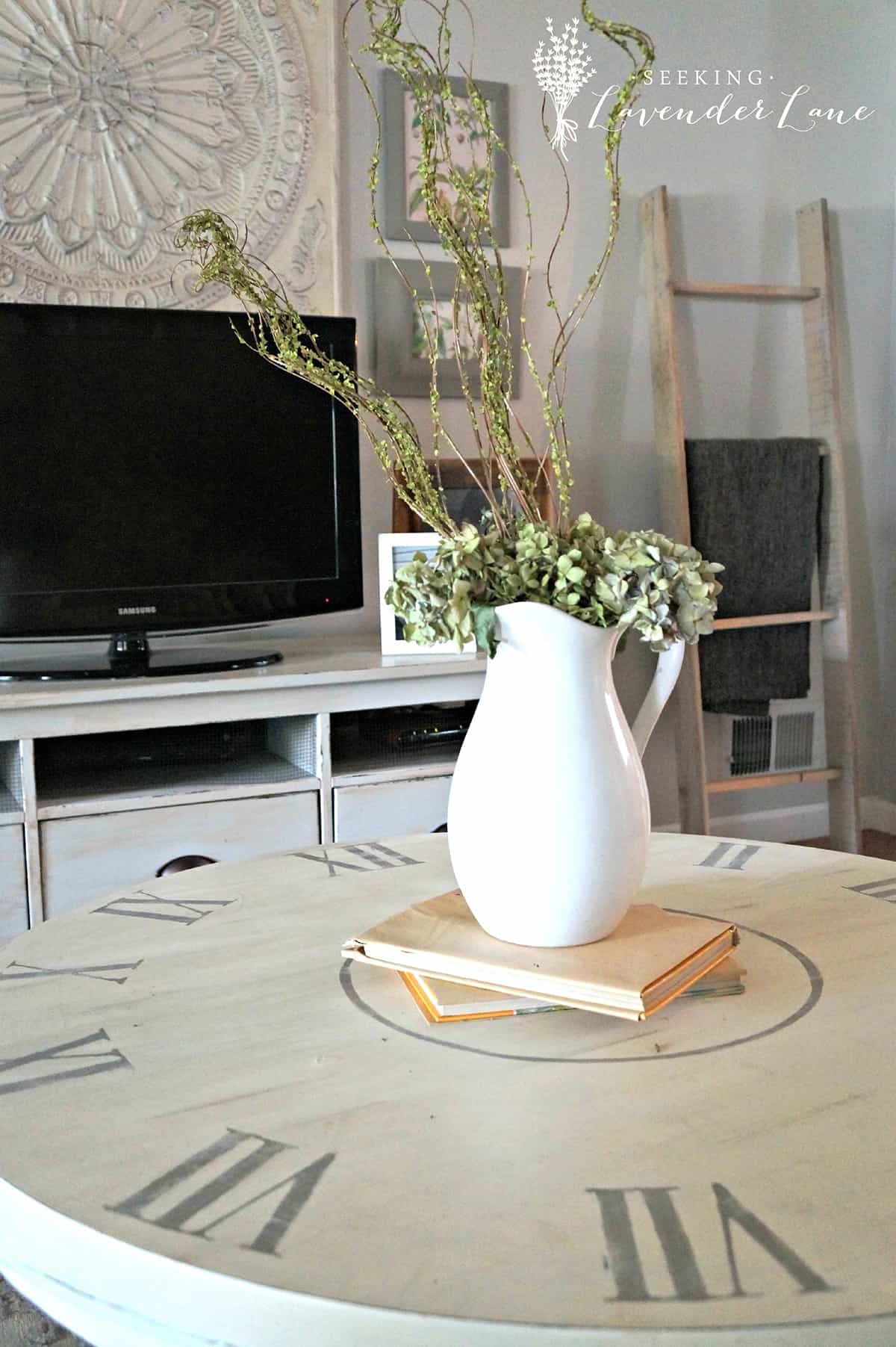 Coffee table painted like a clock with vase and books on top.