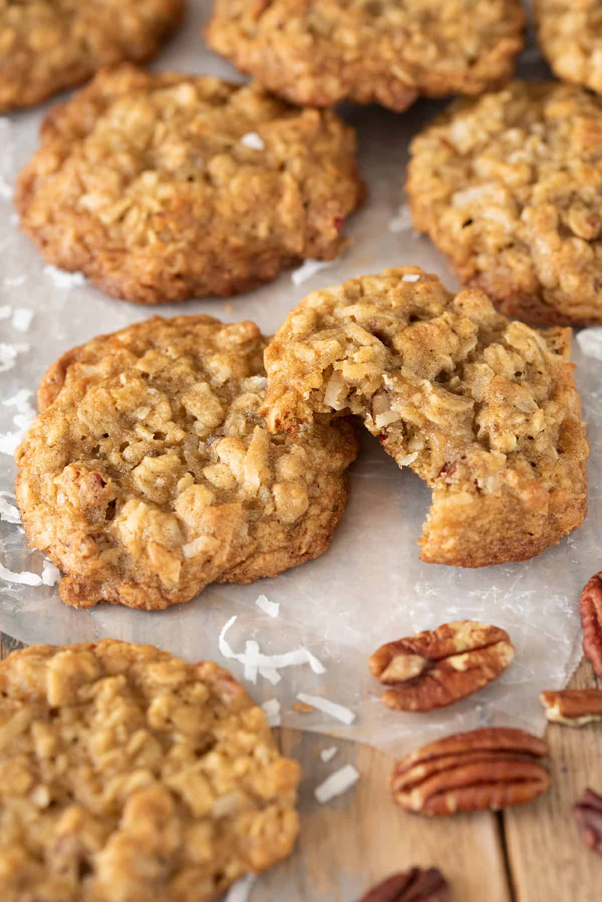 Coconut Pecan Cookies laid out on wax paper. One cookie has a bite taken out to show texture of the cookie.