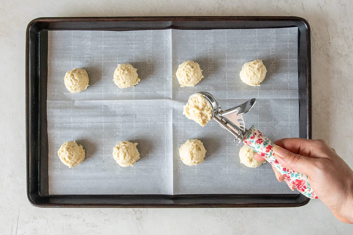 A hand holding a cookie scoop to show how to fill for perfect cookie size.