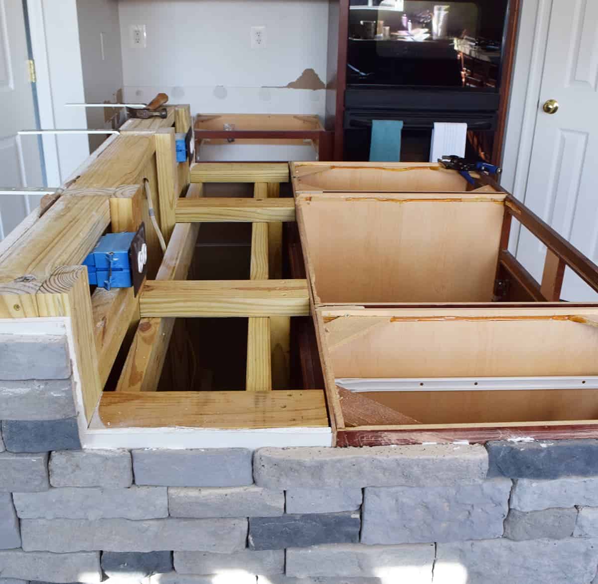 Stone covered kitchen island with raised breakfast bar with stove and countertop removed.