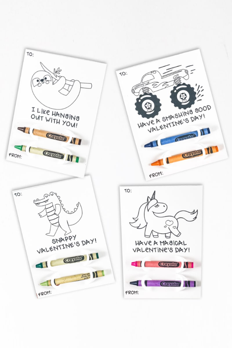 Four valentine's day coloring page drawings with crayons attached.