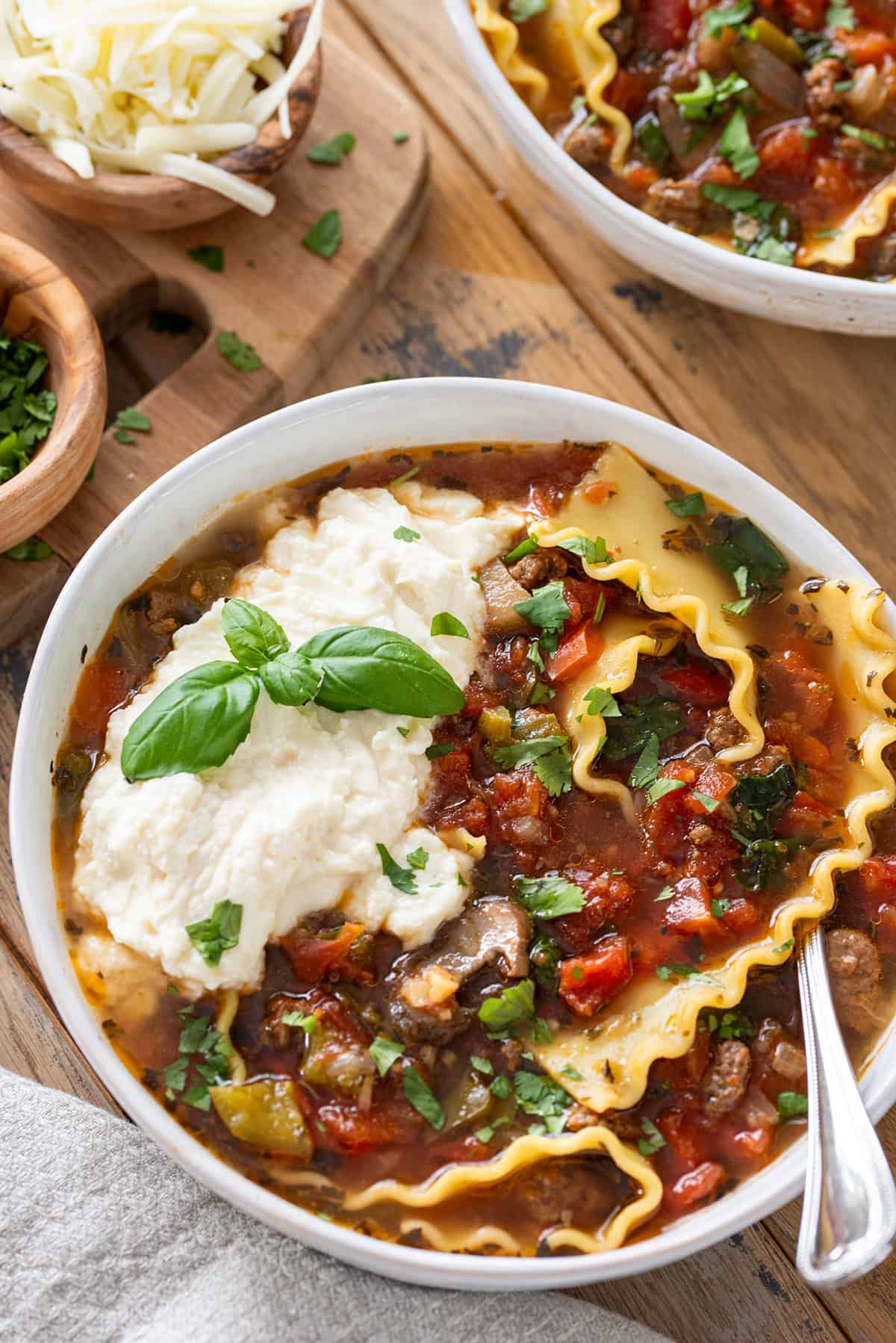 Overhead of bowl of lasagna soup with ricotta cheese and basil on top.