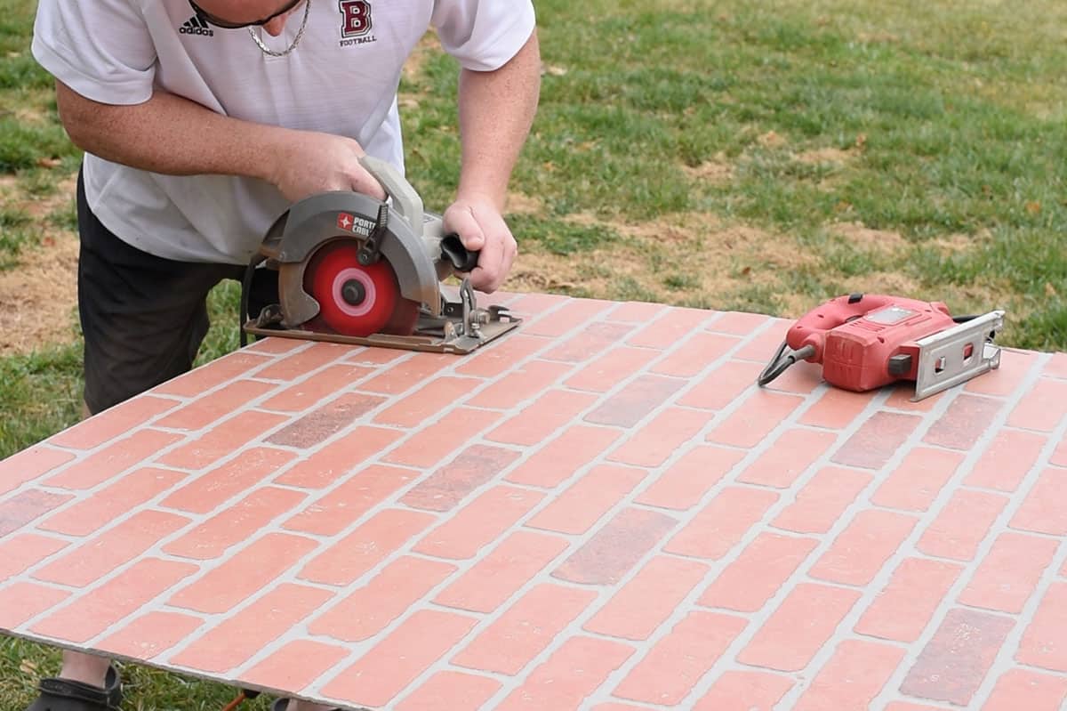Man cutting a panel of cement faux brick wall panel.