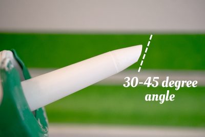 The tip of a caulk gun cut at a 45 degree angle.