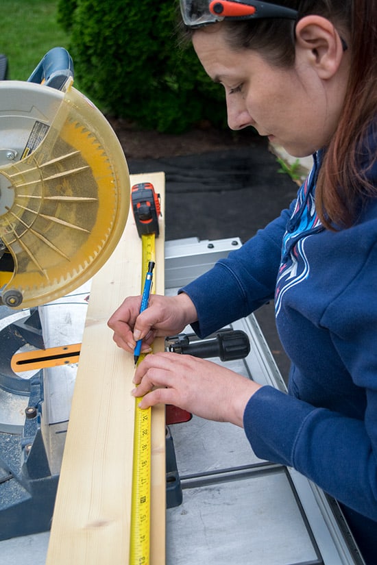 Rachel measuring to cut owood on a mitre saw.