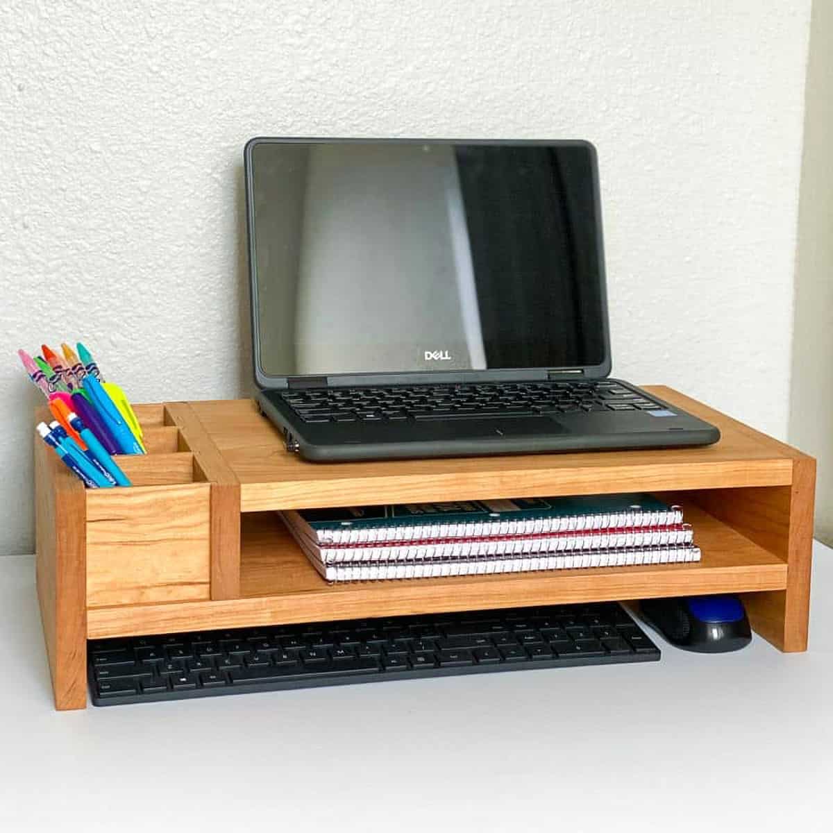Wooden laptop platform with shelf for notebooks and divider slots for pens and pencils.