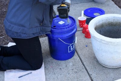 Drilling holes into a bucket lid.