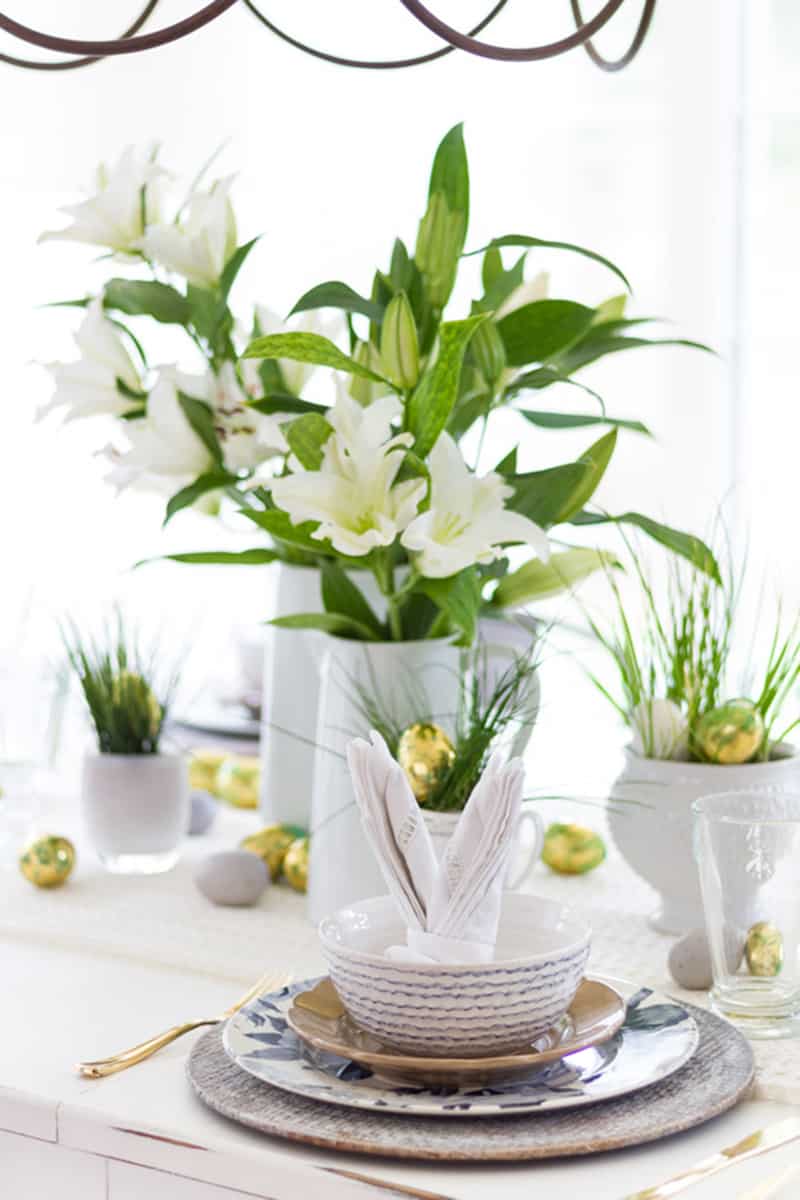 Decorated easter table with bunny napkins and white lillies as centerpieces.