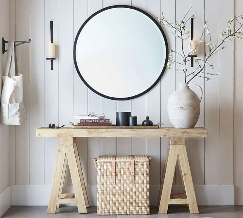 Console table in an entryway with large mirror, candle sconces, and decorative vase on top to decorate the console table.