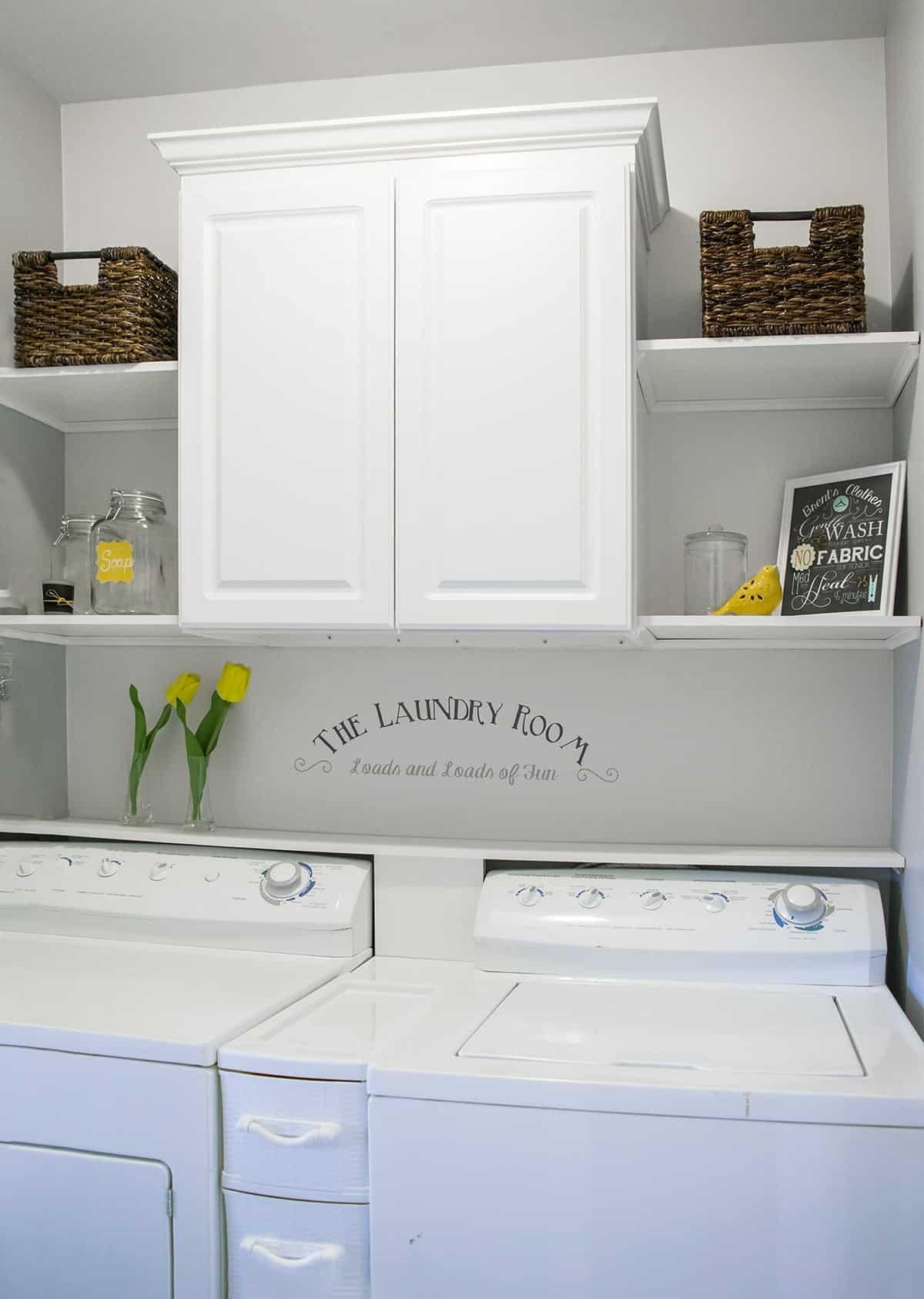 Laundry Room Makeover with cabinet and shelves for storage above the washer and dryer.